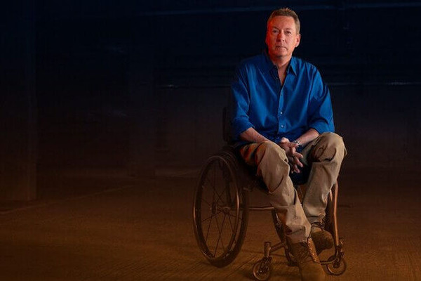 Frank Gardner in a wheelchair in a darkly lit building