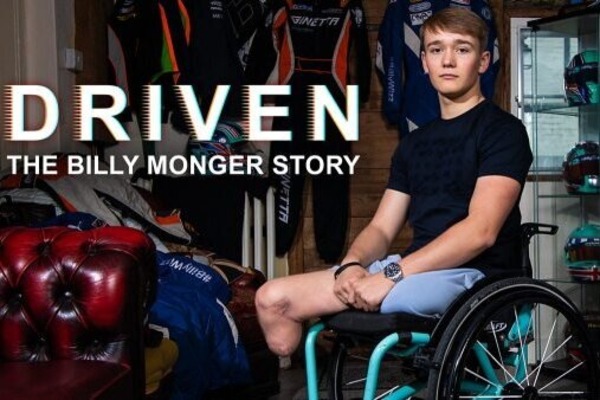 Billy Monger in a wheelchair surrounded by racecar driving memorabilia